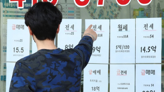 한 시민이 부동산공인중개업소에 게재된 아파트 급매물 시세를 가리키고 있다.<연합뉴스>